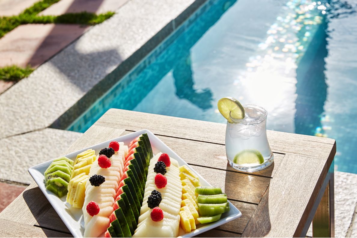 A tray of fruit on a poolside deck chair