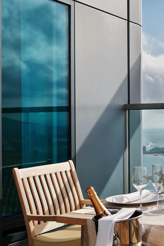 A dining table on a terrace overlooking the city and sea
