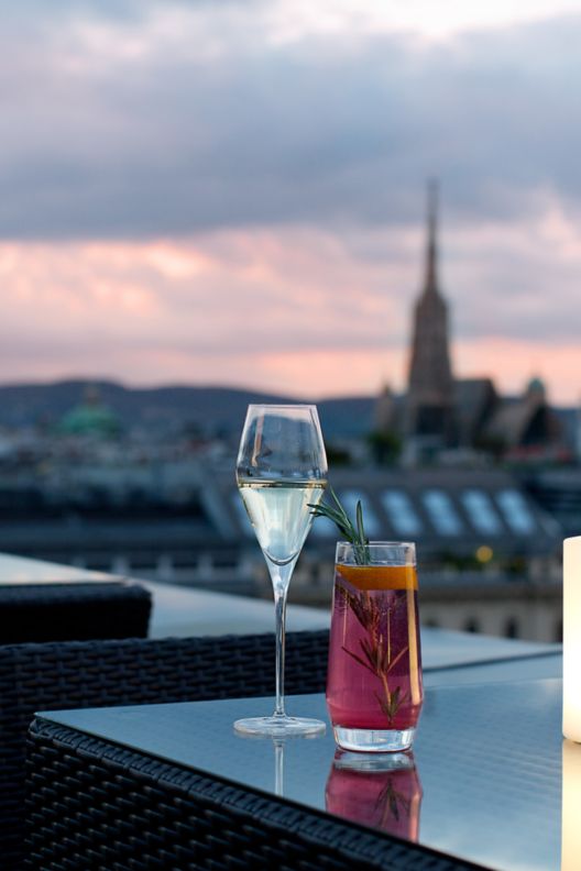 Sunset falling over Vienna with skyline views from the rooftop bar and candles lighting the tables.