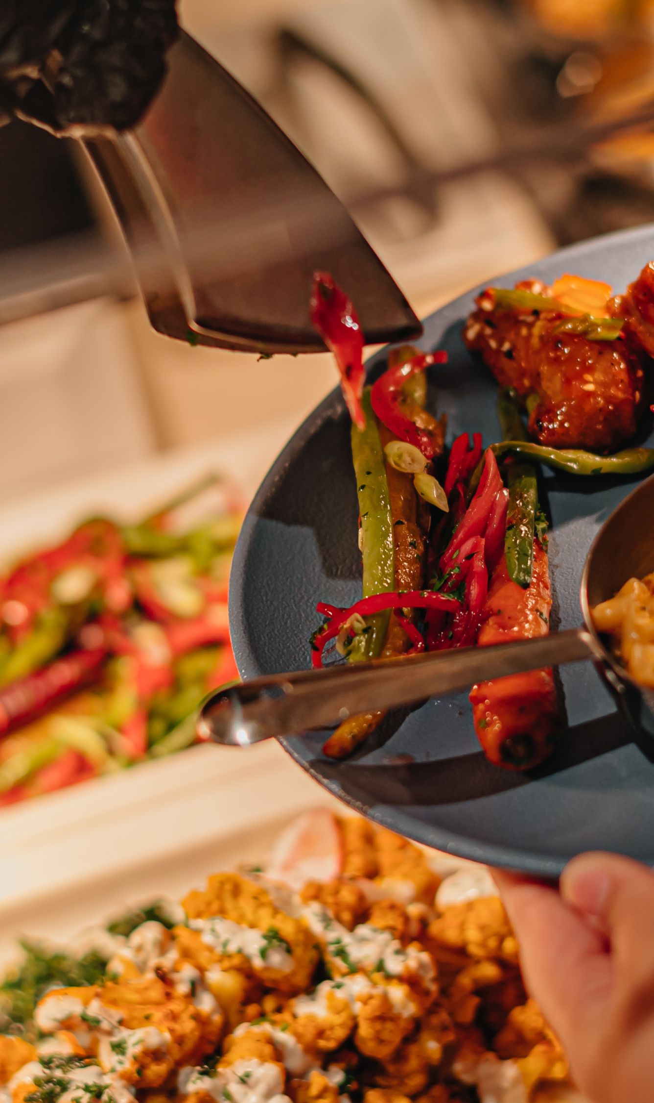 Hands holding a plate serving over a buffet with corn and turkey.