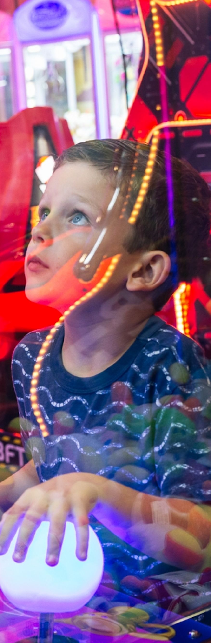 Kid playing a game in an arcade. 