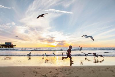 Child running on beach at sunset