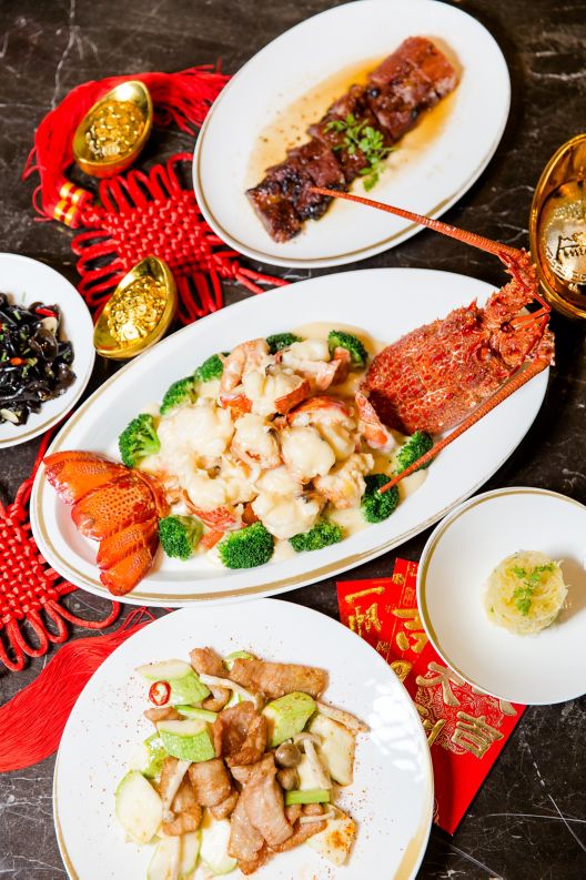 Lavish presentation of lobster, meat and seafood on pristine white plates positioned atop black marble and red  tasseled mats