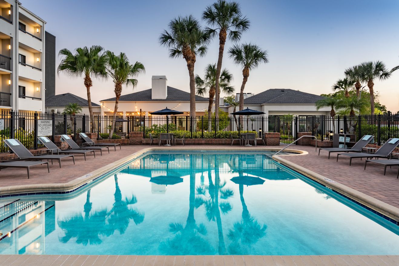 Outdoor pool with chairs and palm trees