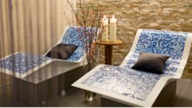 Two undulating blue lounge chairs in a quiet space with two candles and decorative branches
