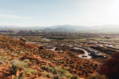 A desert hill with a suburban landscape in the background