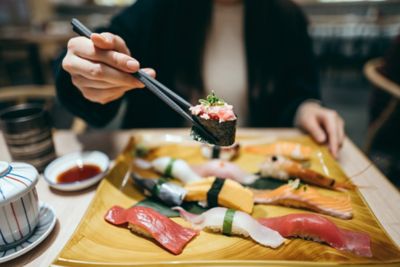 A person holding sushi with chopsticks