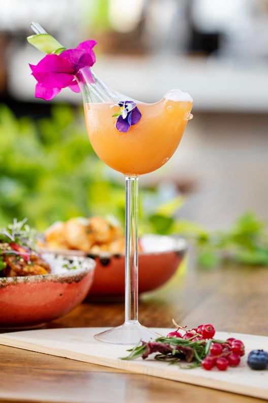 A cocktail with fruit and a flower for decorations.