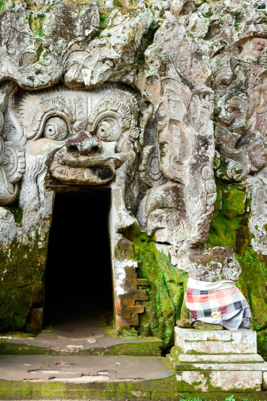 小さな入口の周辺の石に誇張された顔が刻まれている洞窟