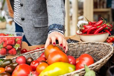Close up of hand picking tomato from basket