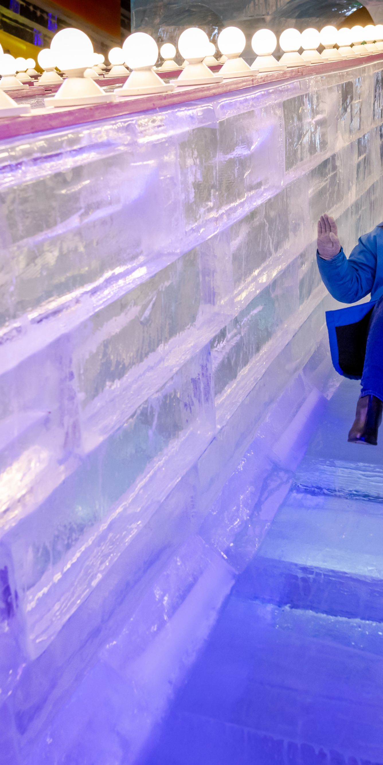 An adult sliding down an ice slide.