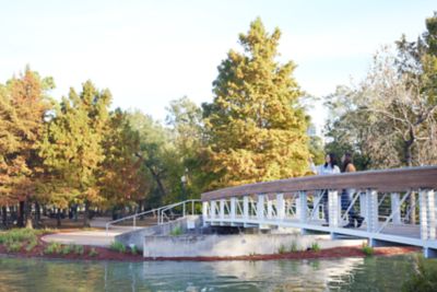Two people walking in park next to manmade pond