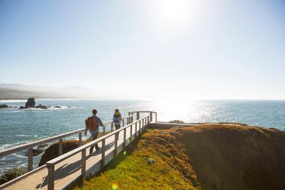 People walking on a boardwalk toward the ocean