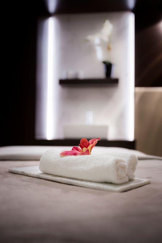 Rolled towels and a flower on a massage bed.