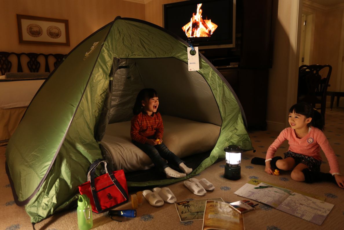 Kids playing in a tent in the hotel room and with toys.
