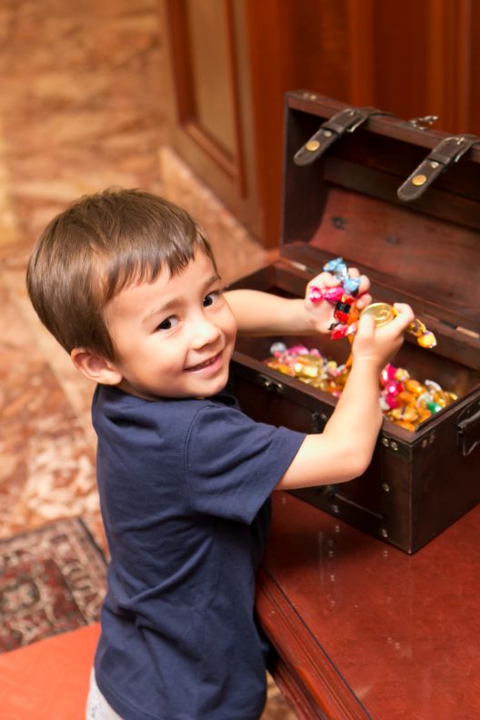 A child getting into a trunk with toys.