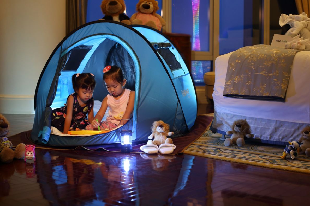 Two children in a small tent in a hotel room.