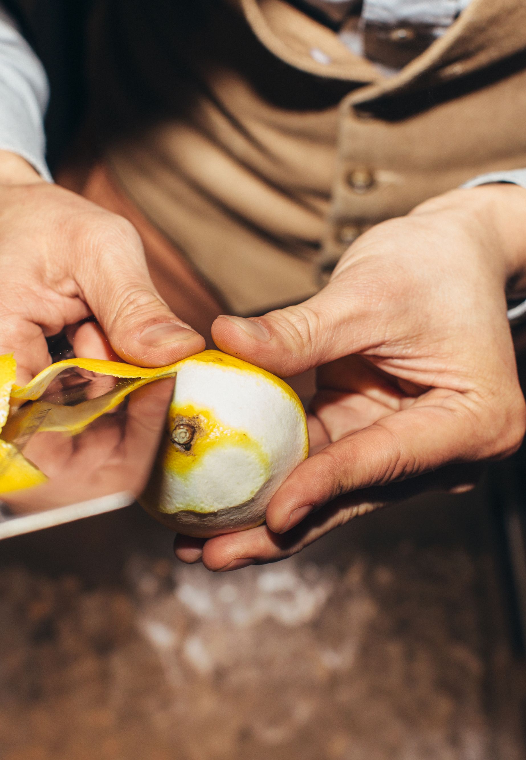 Male Bartender Peeling Lemon in Stylish Dark Bar