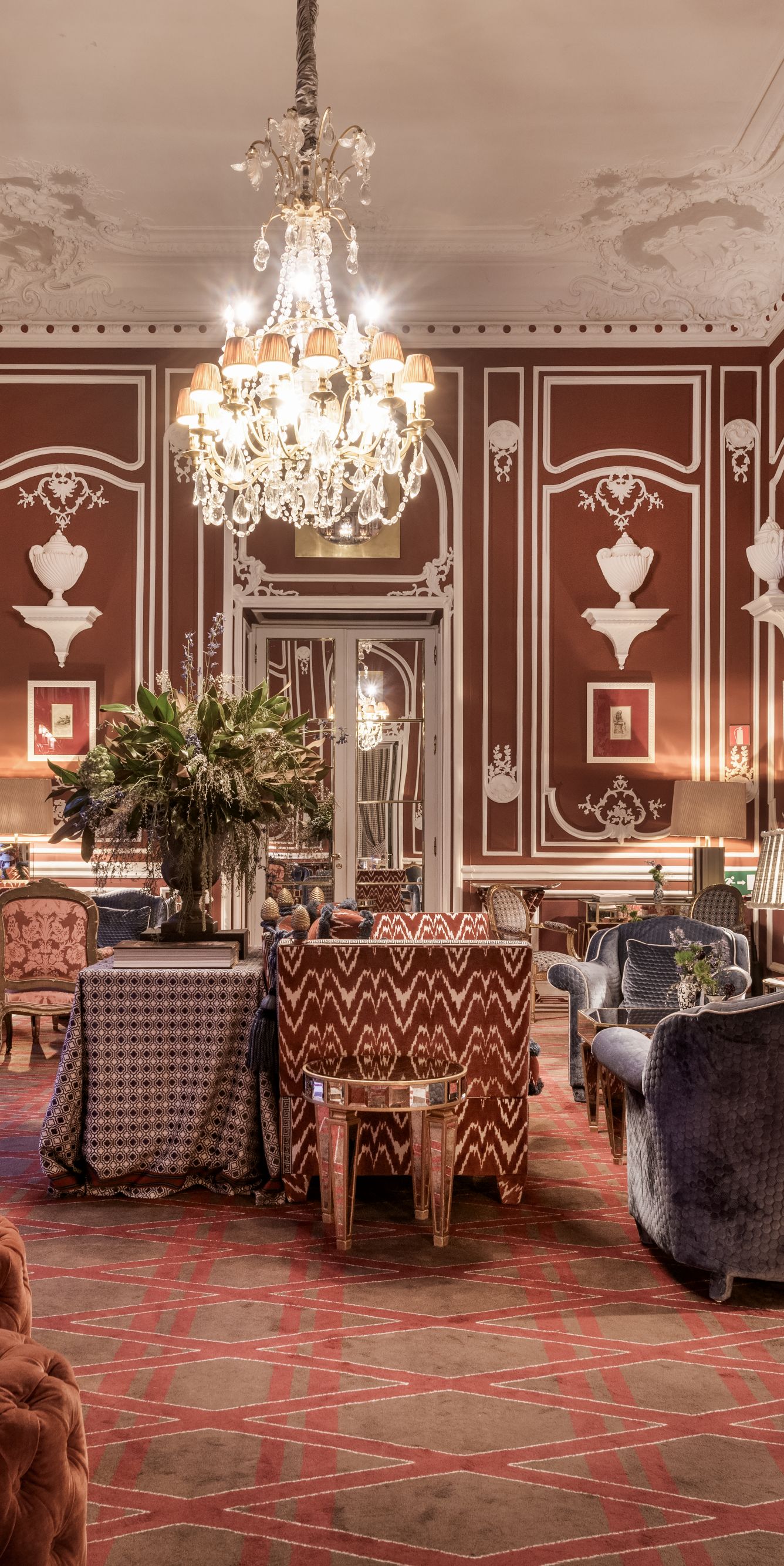 Red Lounge with ornate decorations, tables, chairs, sofas, and a chandelier.
