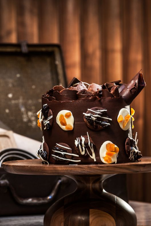 A beautifully decorated chocolate cake on a wood stand.