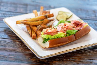 Closeup of lobster roll and fries on a plate.