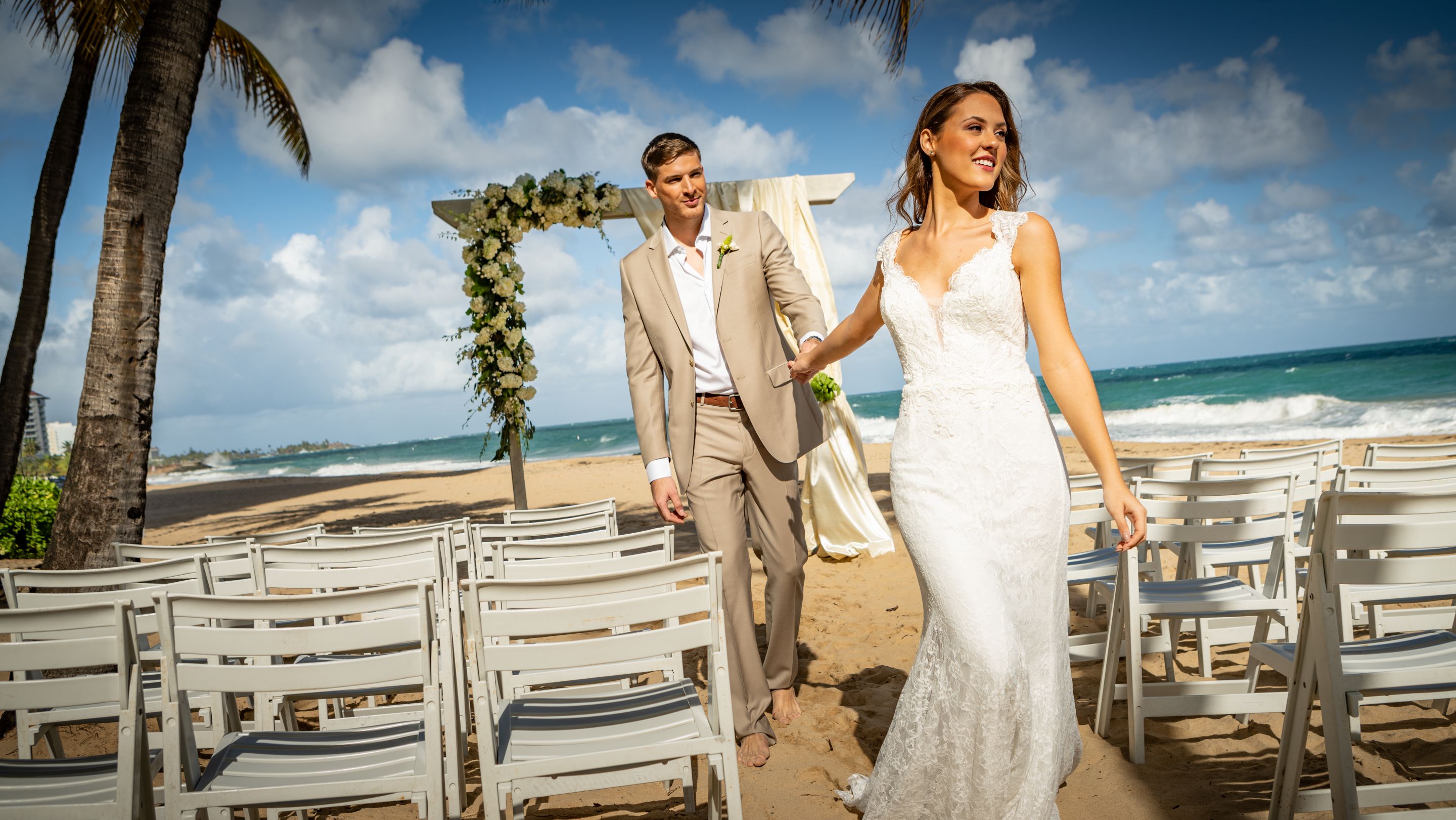 Bride and groom holding hands on a beach and walking down an aisle.