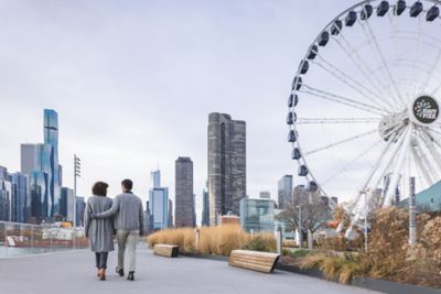 Two people walking on path with Ferris wheel