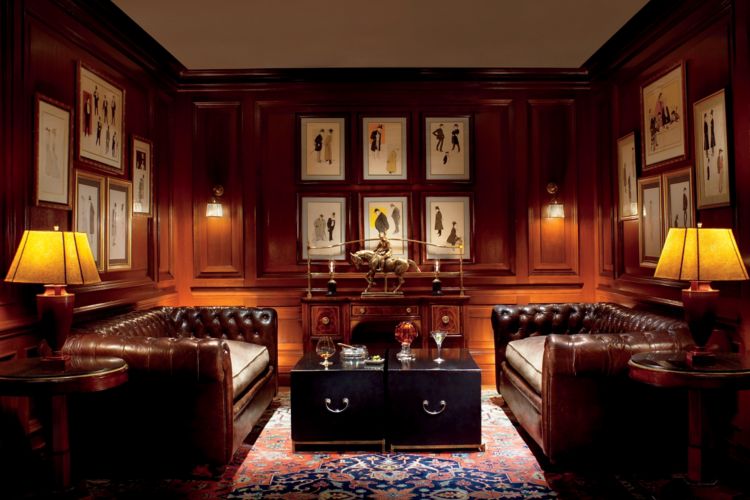 Wood-paneled room with two leather couches and two square tables in the middle with cocktail glasses on top
