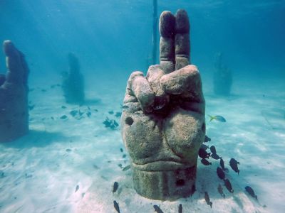 A stone hand sculpture reaches out of the sand