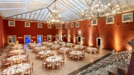 A large space with a vaulted roof, chandeliers, high windows and round banquet tables