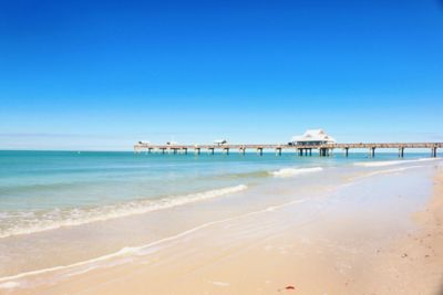 Beach in the sun with pier in the distance