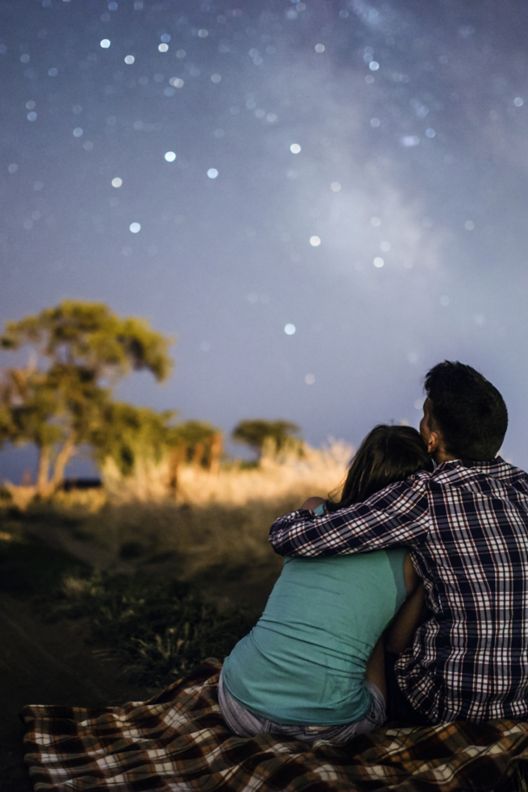 A couple sitting outside looking at the stars.