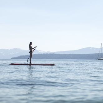 A woman standing on a board in the middle of the lake