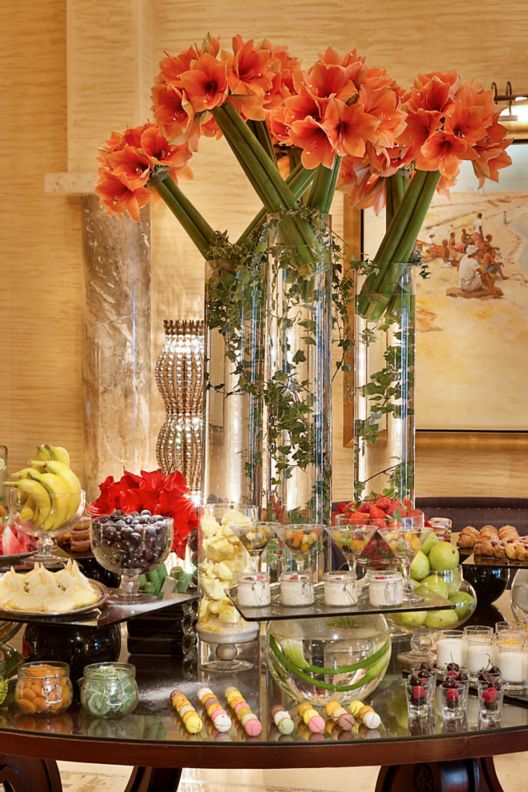 A table set with desserts and a center piece of bright flowers.