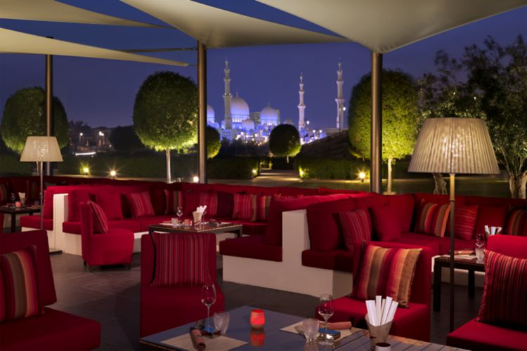 Shaded restaurant terrace at evening with views of the olive grove and mosque