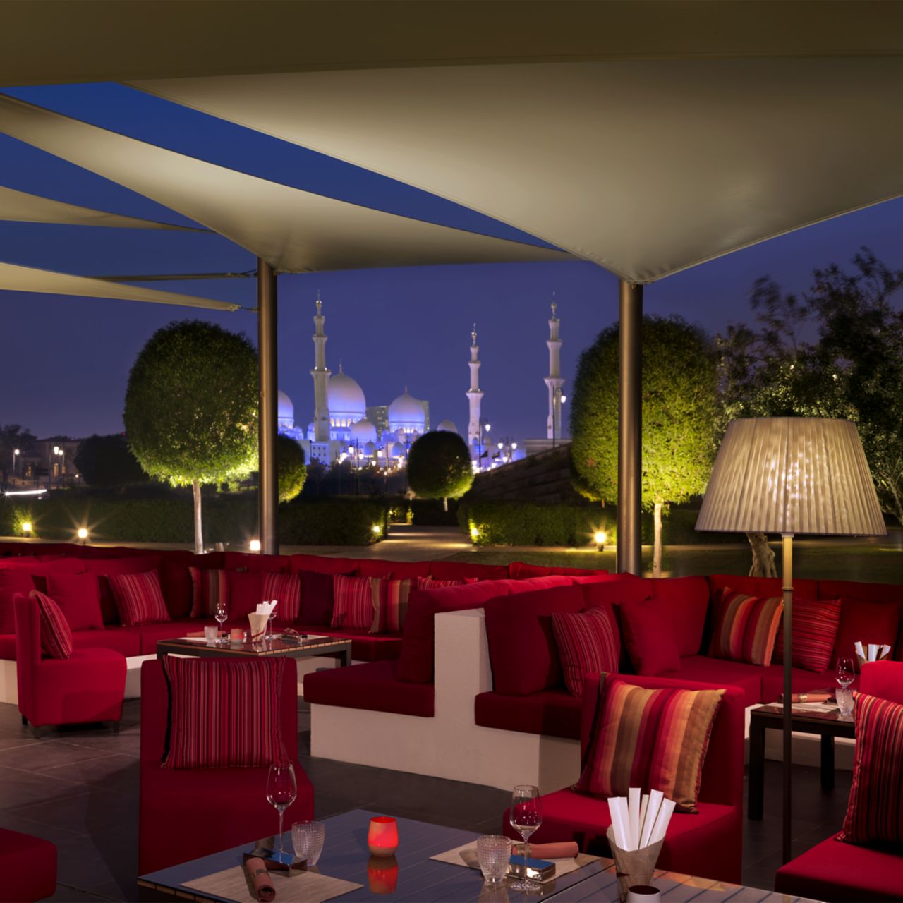 Shaded restaurant terrace at evening with views of the olive grove and mosque