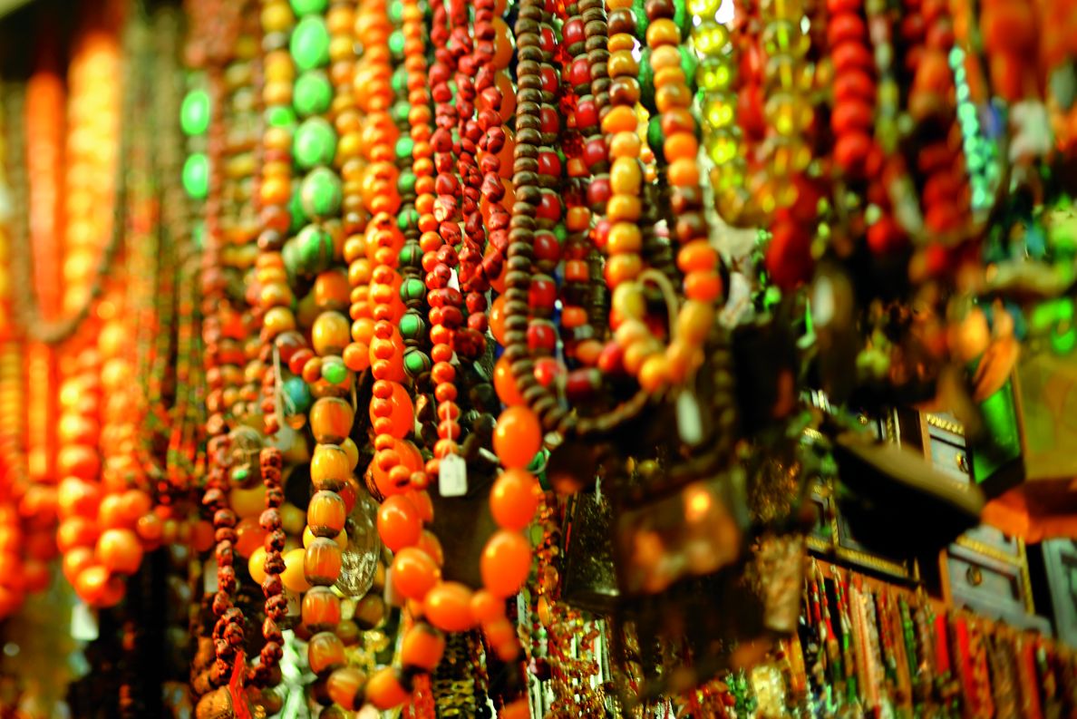 Close up view of several strings of brightly colored hanging bead necklaces.