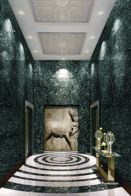 An elevator foyer with marble floors and a large horse wall carving.