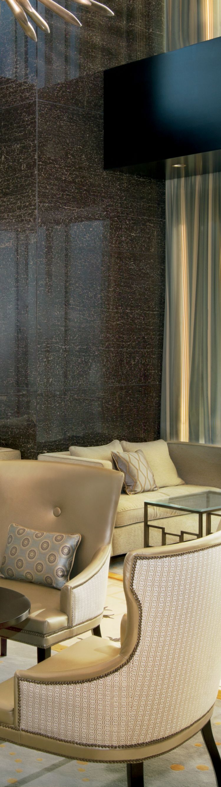 Open space with floor-to-ceiling windows, a sun-like chandelier and multiple seating areas