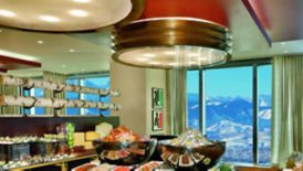 A large buffet spread in a room with floor-to-ceiling windows looking out to snow-capped mountains