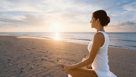 Woman sitting cross-legged in a meditative pose on the beach
