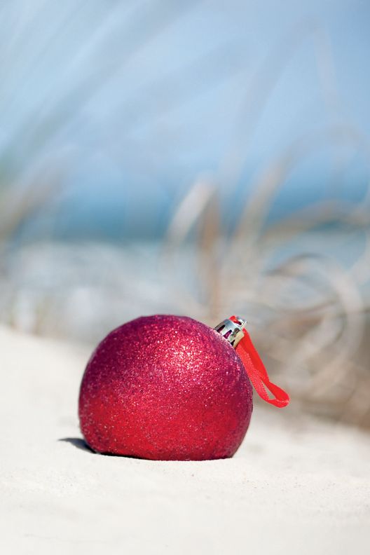 A single Christmas tree ornament in the sand
