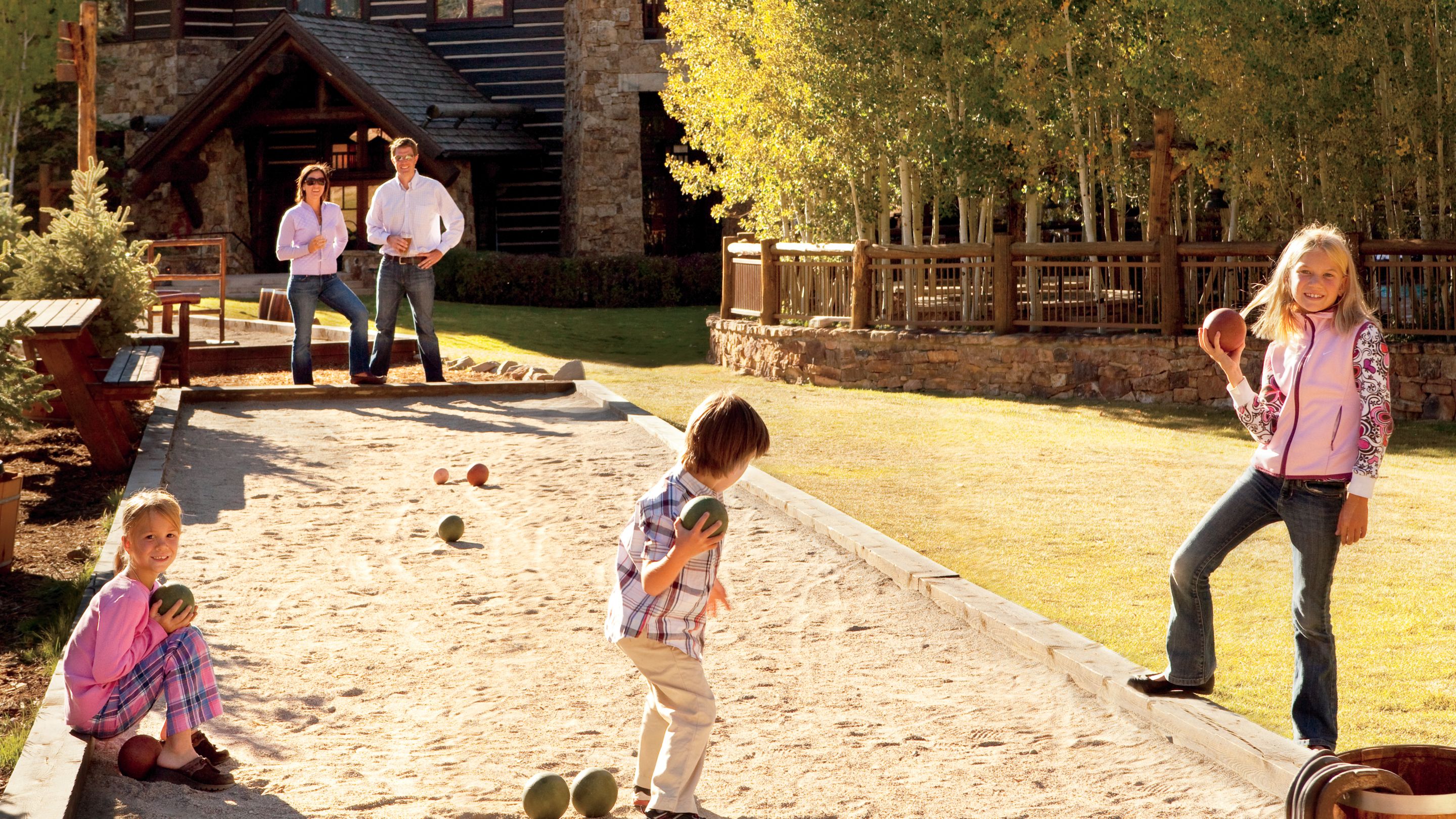 A family of five plays on an outdoor bocce ball court
