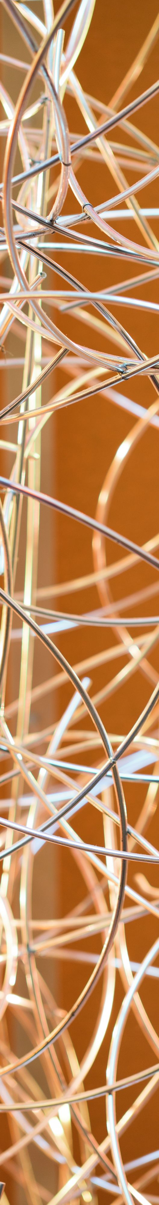 A close up of three dimensional art with wires of gold and silver.