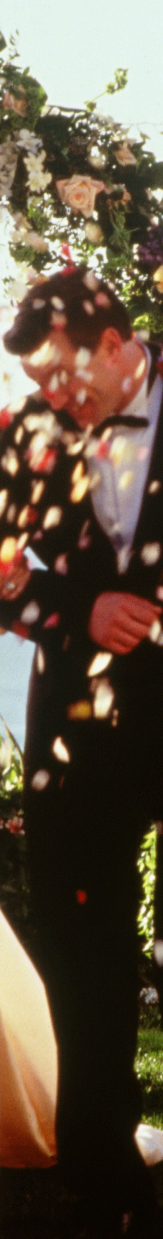 A couple at the altar of their outside wedding with flowers being thrown at them.