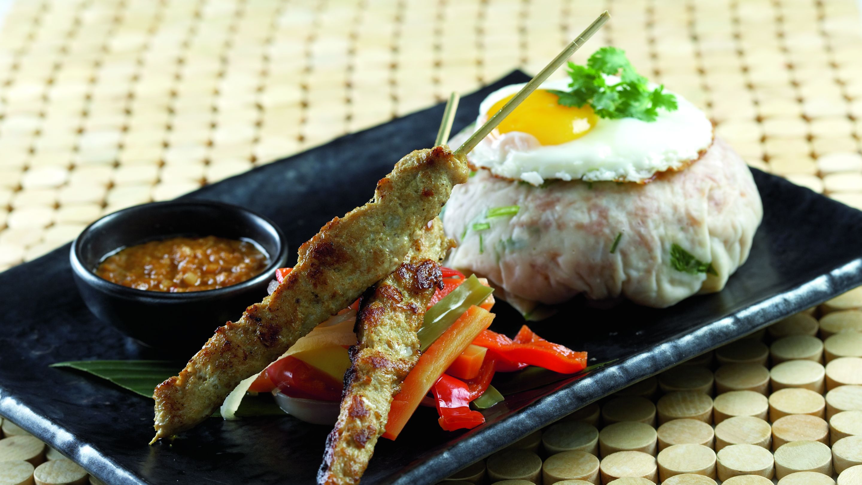 Tray with chicken satay, peppers and a fried egg