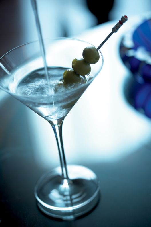 Martini with olives sitting on a table.