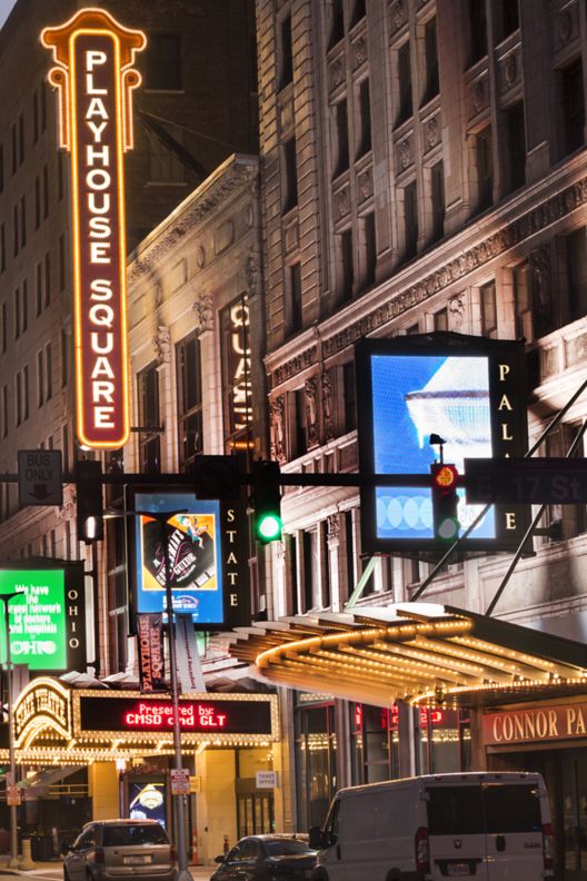 A sign for a theater lights up a city street at night