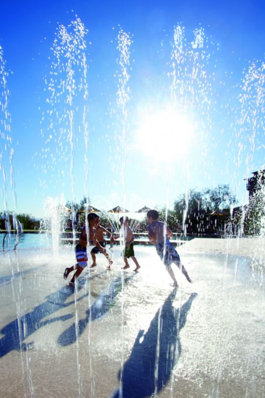 A bunch of kids playing on a splash pad.