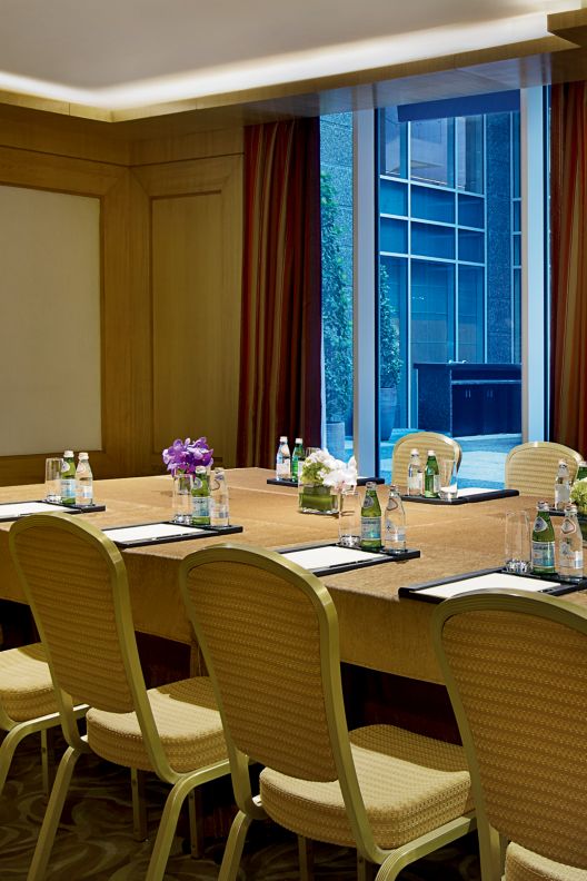 Private meeting room with a rectangular table that has notepads, water & flower decorations.
